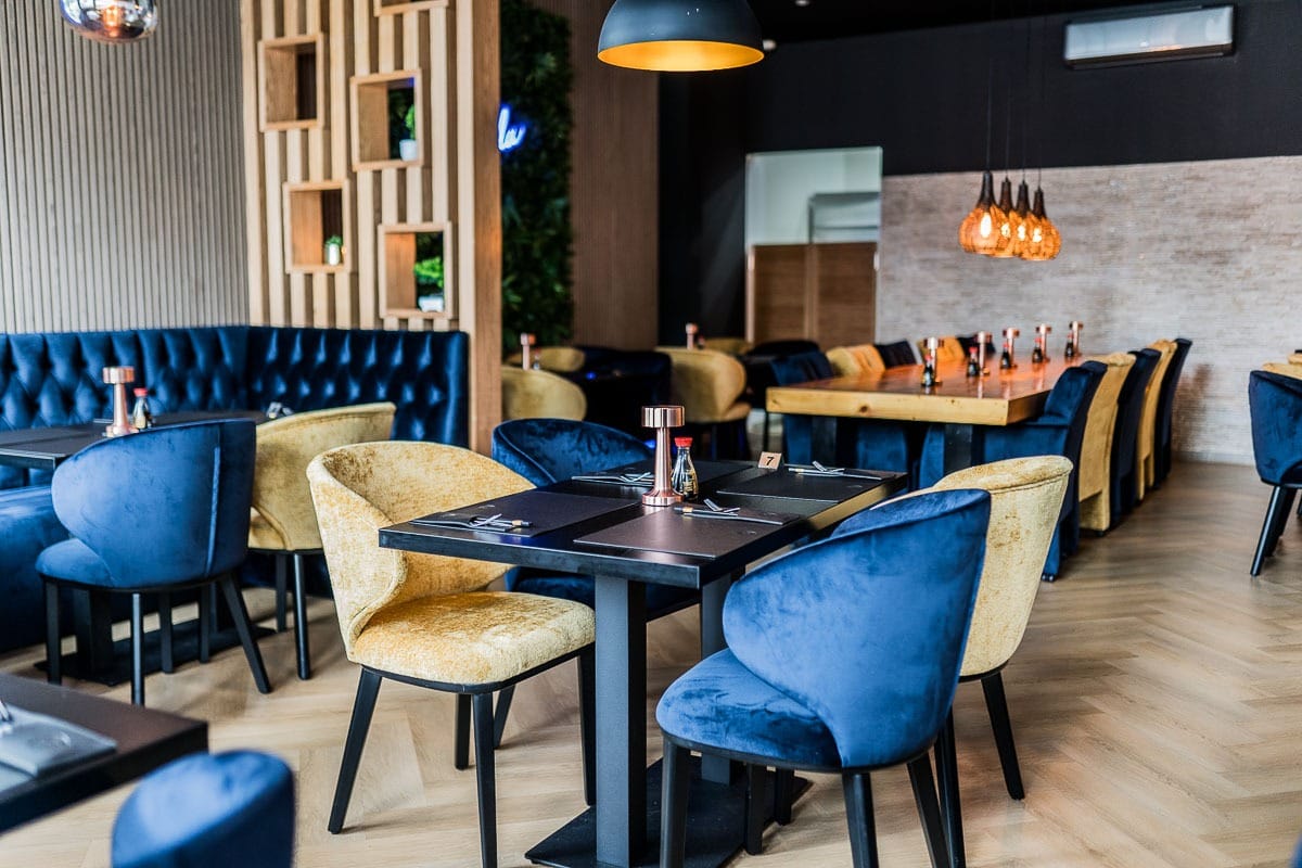 Interieur van het restaurant met blauwe en goudkleurige fluwelen stoelen
